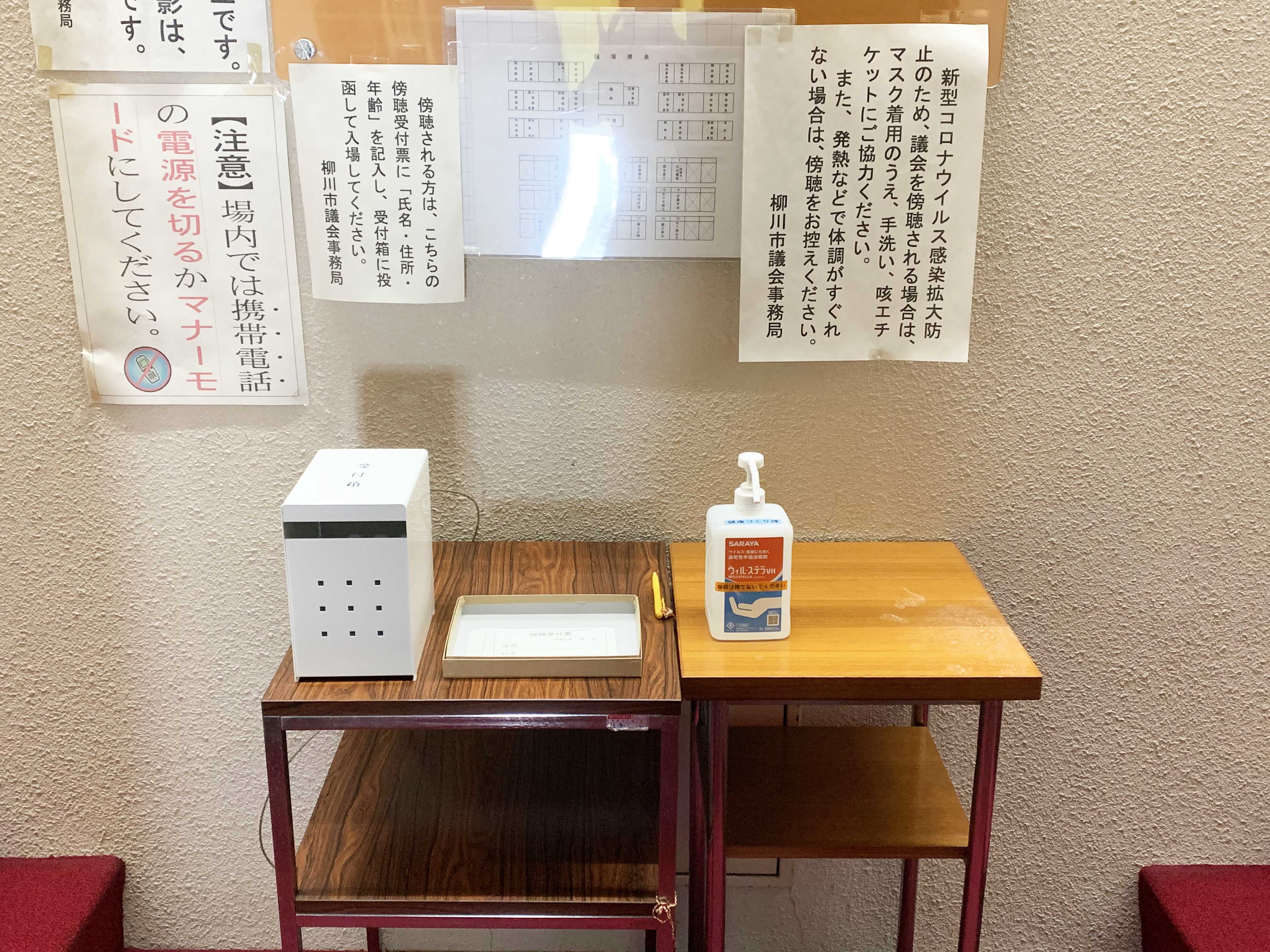 消毒スプレーなどが置いてある傍聴受付の写真